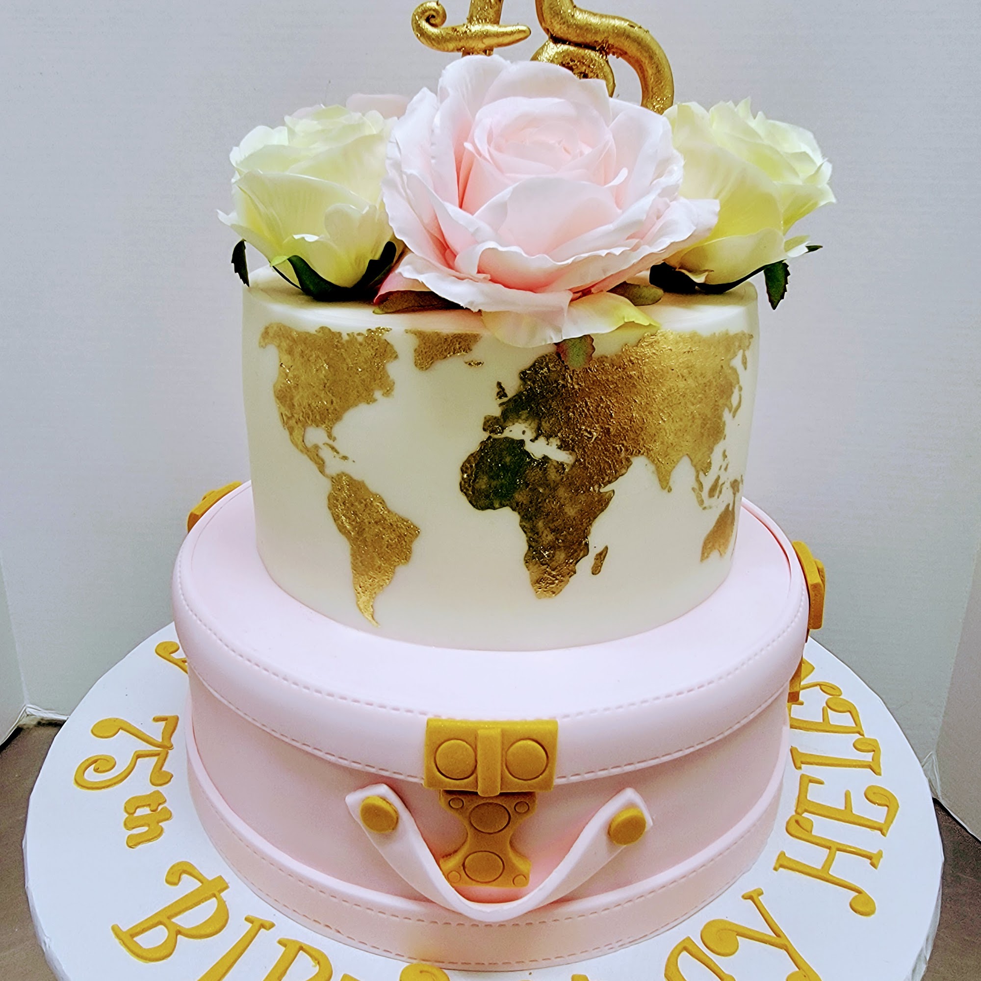 Gâteau deux étages 75e anniversaire d'Helen : valise rose sculptée, carte du monde en or, roses et topper 75.